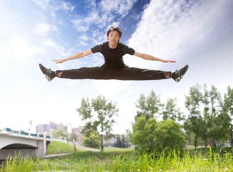 Young man jumping in the air near bridge under clear sky