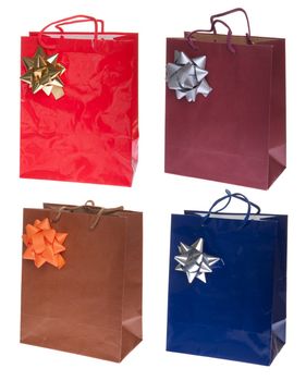 four colorful gift paper bags with bows isolated on white background