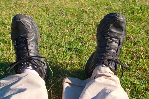 Traveler feet against a green field: the picture for traveling, hiking, health, legs, sports shoes