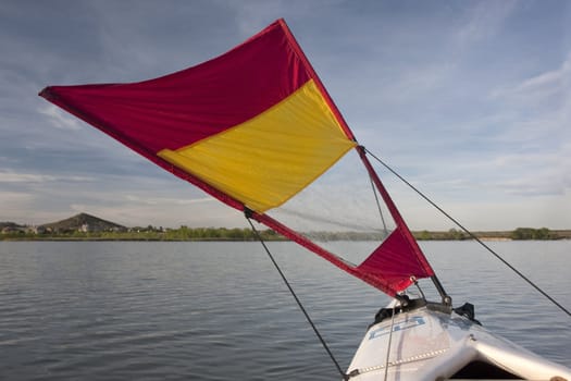 kayak sailing on lake with small triangular downwind sail mounted on bow,  thirteen is a temporary racing number put on boat deck by myself