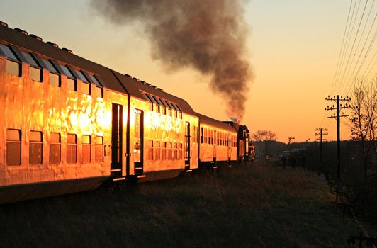 Steam train starting from the station during sunset