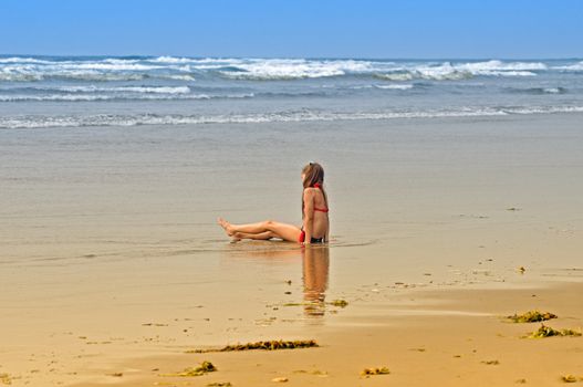 A girl sunbathing on the beach of the  Pacific Ocean.
