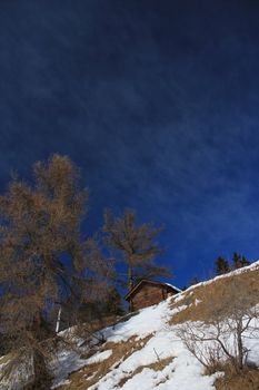 Small wood chalet in the Alps mountain by beautiful winter day, Switzerland