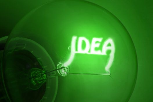 Close up of green illuminated light bulb filament spelling the word "IDEA"