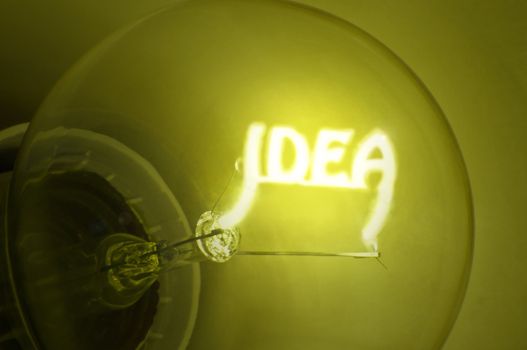 Close up of yellow illuminated light bulb filament spelling the word "IDEA"