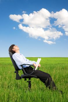 Businessman relaxing on green grassland under blue sky