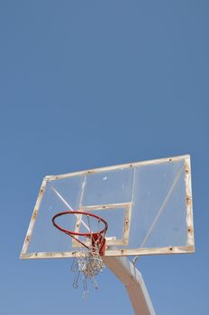 old outdoor basketball hoop against blue sky background