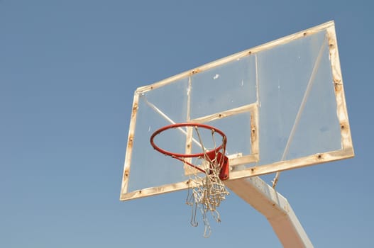 old outdoor basketball hoop against blue sky background