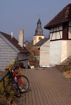 Modern bike in old German town, belltower between traditional old houses, town Heimbach, Germany
