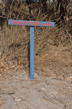 blue toilet sign at the beach (german language)