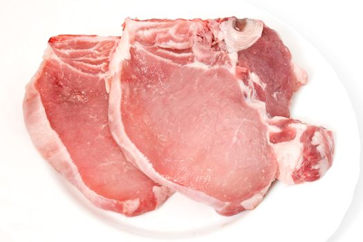 two fresh raw pork chop on a white plate 