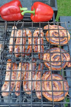 grilling fresh sausages and pepers on a outdoor barbecue