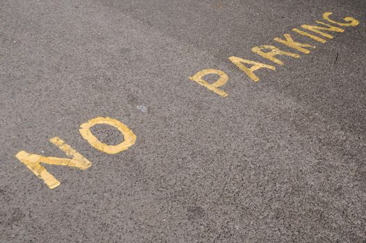 yellow painted no parking sign on the asphalt