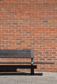 wooden bench against a brick wall building