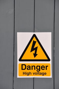 high voltage danger yellow sign on a wooden plank background