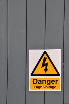 high voltage danger yellow sign on a wooden plank background