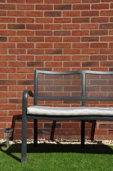 outdoor bench at a grass garden (brick wall background)