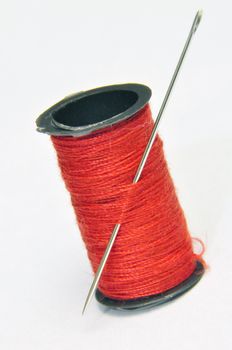 Spool of thread and needle on white background