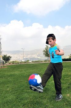 	
A boy plays with ball on the grass in the park
