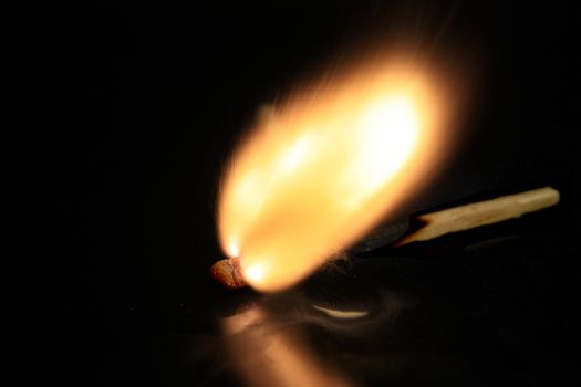 Match burning on black surface