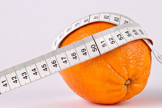 Orange fruit with tape measure on white background