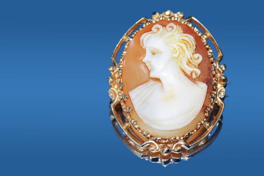 Fine jewelry: beautiful antique cameo on blue reflective background.