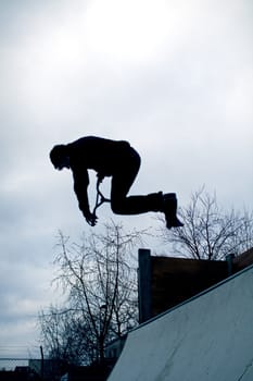 A teenager jumping of a springboard with its trotinette