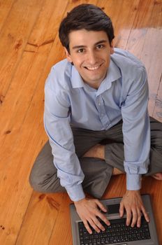 attractive young man with laptop computer sitting on the floor at home