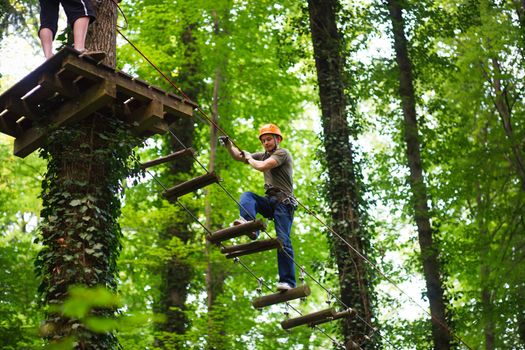 Courageous boy taking a big risky step while he is connected to a safety line