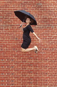 Lady jumping with umbrella high into air.