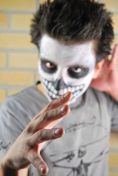 Evil look and hand, portrait of a creepy skeleton guy perfect for Carnival (brick wall background)
