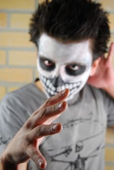 Evil look and hand, portrait of a creepy skeleton guy perfect for Carnival (brick wall background)
