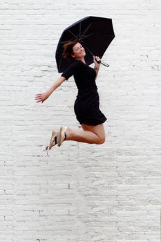 Lady jumping with umbrella high into air.