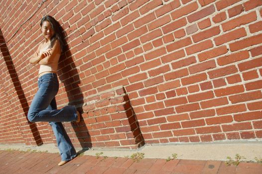 Fashionable young woman against red brick wall.