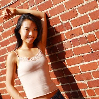 Fashionable young woman against red brick wall.