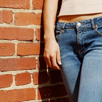 Fashionable closeups of womans mid section against brick wall.