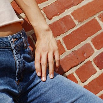 Fashionable closeups of womans mid section against brick wall.