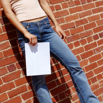 Fashionable girl against red brick wall with blank paper.