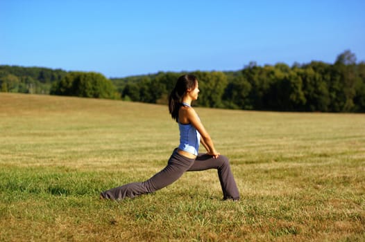 Girl practicing yoga in a summer meadow.