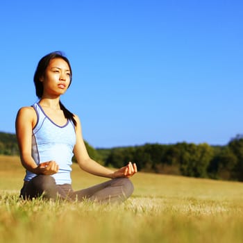 Girl practicing yoga in a summer meadow.