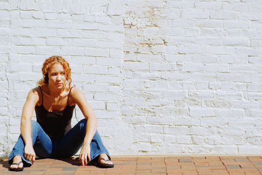 Attractive urban girl against white brick wall.