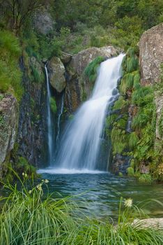 A waterfall surrounded by rocks and some vegetation.