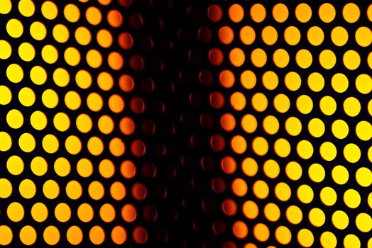 A metalic reflective surface back lit by a colorful light.