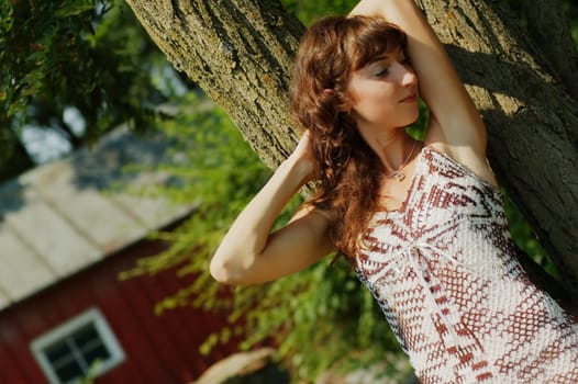Pretty girl leaning against a tree.
