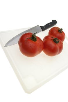 Cutting board with a knife and tomato isolated on a white background.