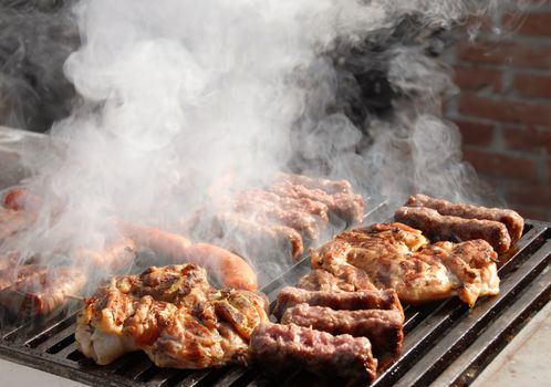 various meat grilled on barbecue in smoke closeup