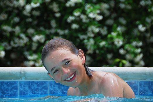Smiling teen boy in swimming pool with flower background.