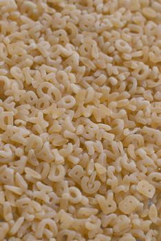 Close-up background of alphabet noodle showing letters.