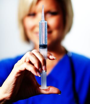 Mature woman nurse holding up a syringe and smiling.