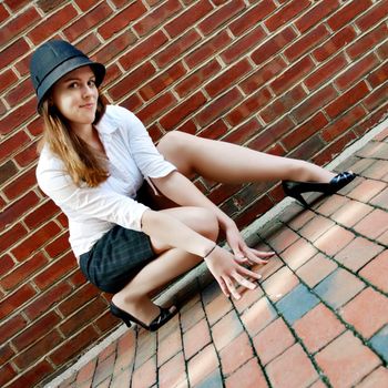 Fashionable young woman posing in front of a brick wall.